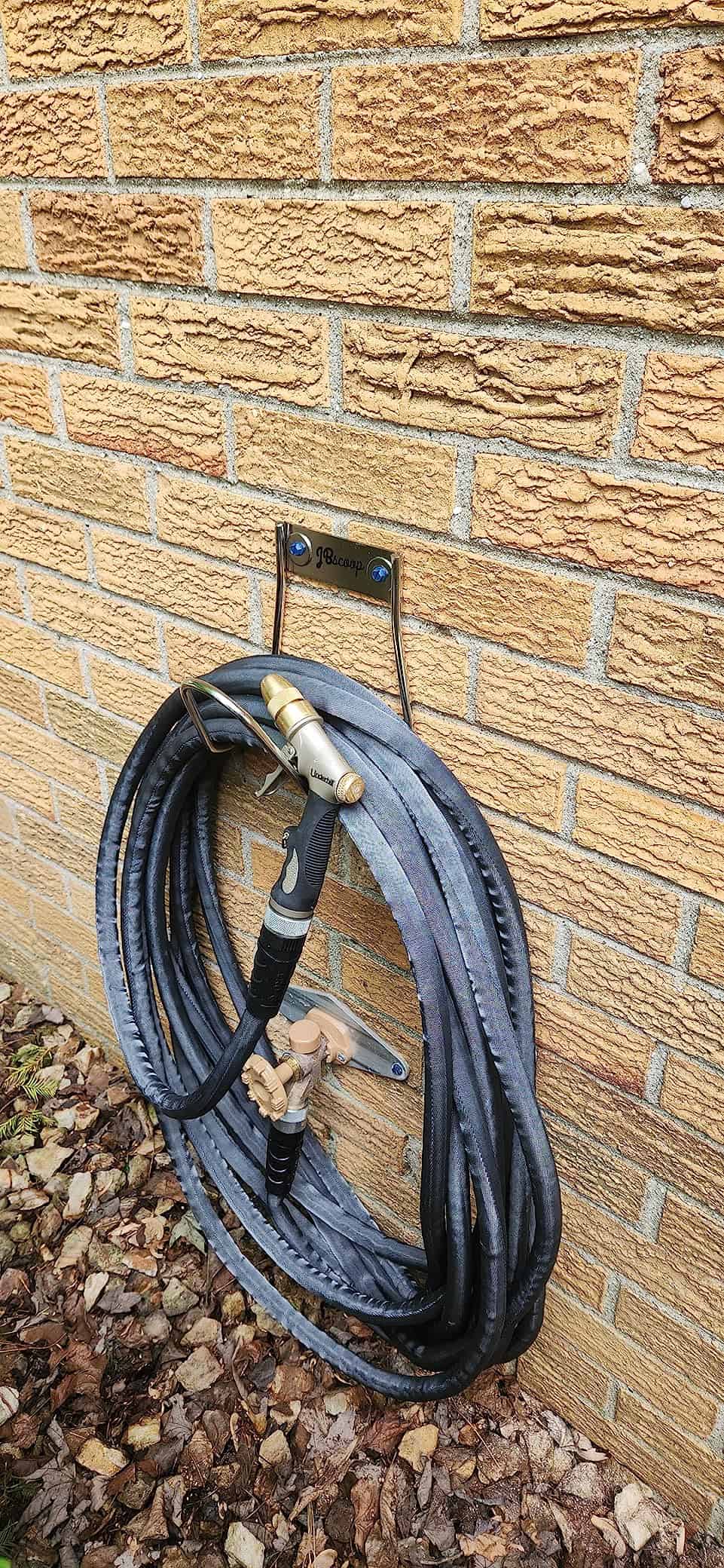 garden hose holder mounted to brick wall